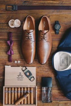 an assortment of men's clothing and accessories laid out on a wooden floor next to a watch