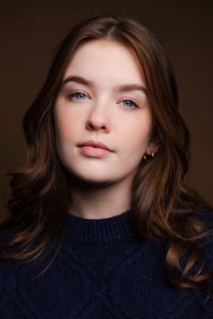 a young woman with blue eyes and long hair wearing a turtle neck sweater looking at the camera