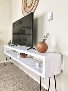 a flat screen tv sitting on top of a white shelf next to a potted plant