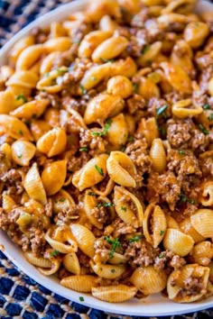 pasta with ground beef in a white bowl on a blue and brown tablecloth, top view