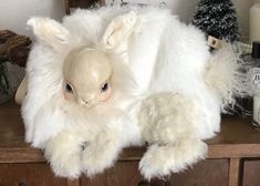 a white stuffed animal sitting on top of a wooden table