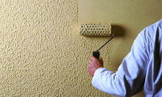 a man using a paint roller to paint a wall with yellow and brown colors on it