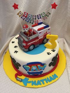 a birthday cake with a firetruck and paw patrol theme on the bottom tier