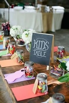 a table topped with lots of candy and jars filled with candies next to a sign that says kids table