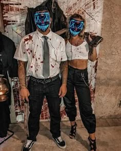 two people wearing masks and standing next to each other