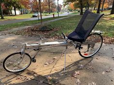 a bicycle with a seat attached to it parked on the sidewalk in front of some trees