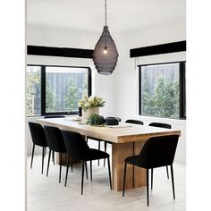 a dining room table with black chairs and a light fixture hanging from it's ceiling