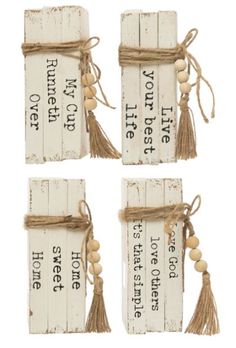 four pieces of wood with tassels tied to each other and words on them