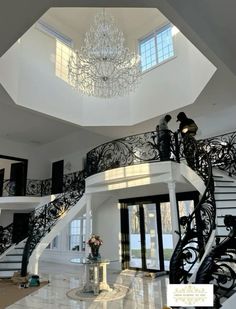 an elegant staircase with chandelier and marble flooring in a large white house