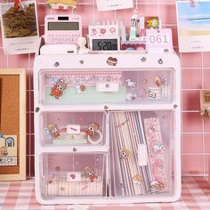 a pink and white shelf filled with lots of items on top of a checkered tablecloth