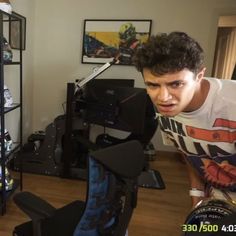 a young man is looking at the camera in his living room, while he's trying to figure out what shoes are for him