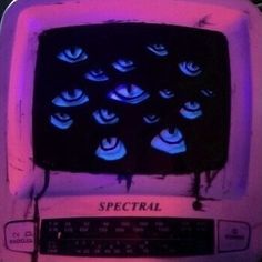 an old fashioned television with blue eyes on it's screen and purple light coming from the back