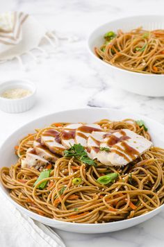 two white bowls filled with chicken lo mein and carrots on top of a marble table