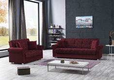 a living room with two red couches and a coffee table in front of a large window