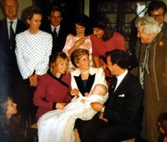 a group of people standing and sitting around each other in front of a man holding a baby