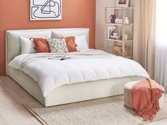 a bedroom with an orange accent wall and white bed in the corner, along with a rug on the floor