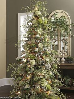 a decorated christmas tree in the corner of a room with a mirror on the wall