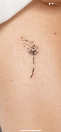 the back of a woman's stomach with a dandelion tattoo on it