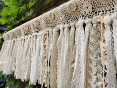 several pieces of crocheted lace hanging from a tree