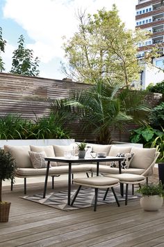 an outdoor patio with furniture and potted plants on the deck, in front of a cityscape