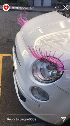 the front end of a white car with pink eyelashes on it