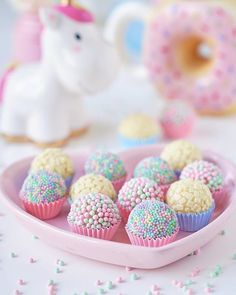 small cupcakes with sprinkles on a pink plate next to a unicorn figurine