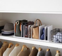 several purses and handbags are hanging on the wall in this closet with white shelving