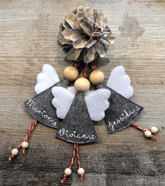 an angel ornament with pinecone and hearts on it, sitting on top of a wooden table