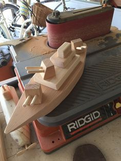 a wooden model of a boat sitting on top of a workbench