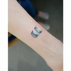 a small blue and white cup tattoo on the wrist