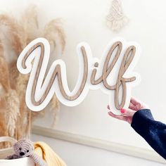 a person holding up a wooden cut out of the word'wife'in front of a wall