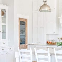 a kitchen with white cabinets and an island in front of the counter top, has chairs around it