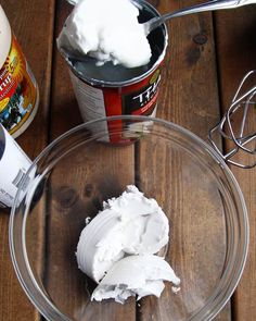 whipped cream is in a bowl next to an ice cream shaker and two spoons