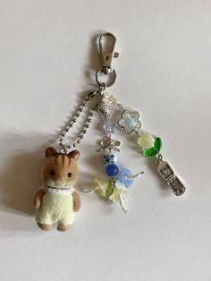 a keychain with a teddy bear and other charms attached to it on a white surface