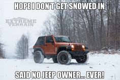 a red jeep is driving through the snow in front of some trees and bushes with its lights on