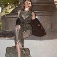 a woman sitting on top of a cement wall next to a statue with chains around her neck