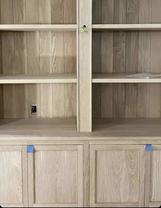 a wooden bookcase with blue tape on the bottom and two open shelves above it