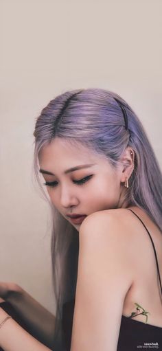 a woman with purple hair is looking down at her cell phone while wearing a black tank top