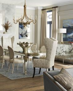 an elegant dining room with white walls and wood flooring, beige upholstered chairs