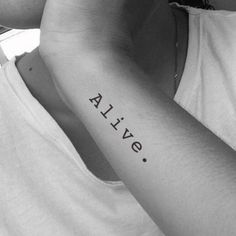 a person with a tattoo that says alive on their arm and the word alive written in black ink