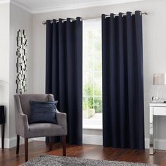 a living room filled with furniture and a window covered in blue drapes, next to a rug