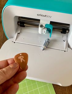 a hand holding a rock next to a cricutjoy machine