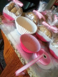 there are many cupcakes and muffins on the table with pink ribbons