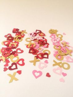 valentine's day confetti cutouts are laid out on a white surface