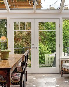 a dining room with french doors leading to an outside deck and patio area that overlooks the trees