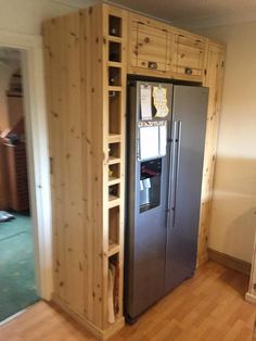 a refrigerator in the middle of a room with wood paneling on the walls and floor