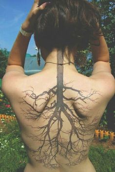 the back of a woman's body with tree roots on her upper and lower back