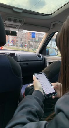 a woman sitting in the back seat of a car holding a tablet