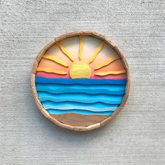 a wooden bowl that has been painted to look like the sun and ocean on it