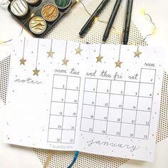 a calendar with gold stars on it sitting next to some paint brushes and other crafting supplies